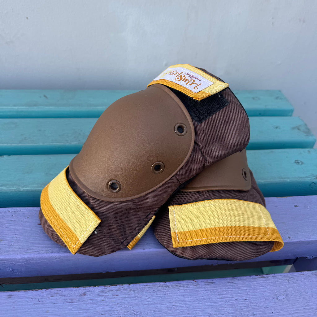 Pair of brown knee pads with yellow accents on a blue and gray background