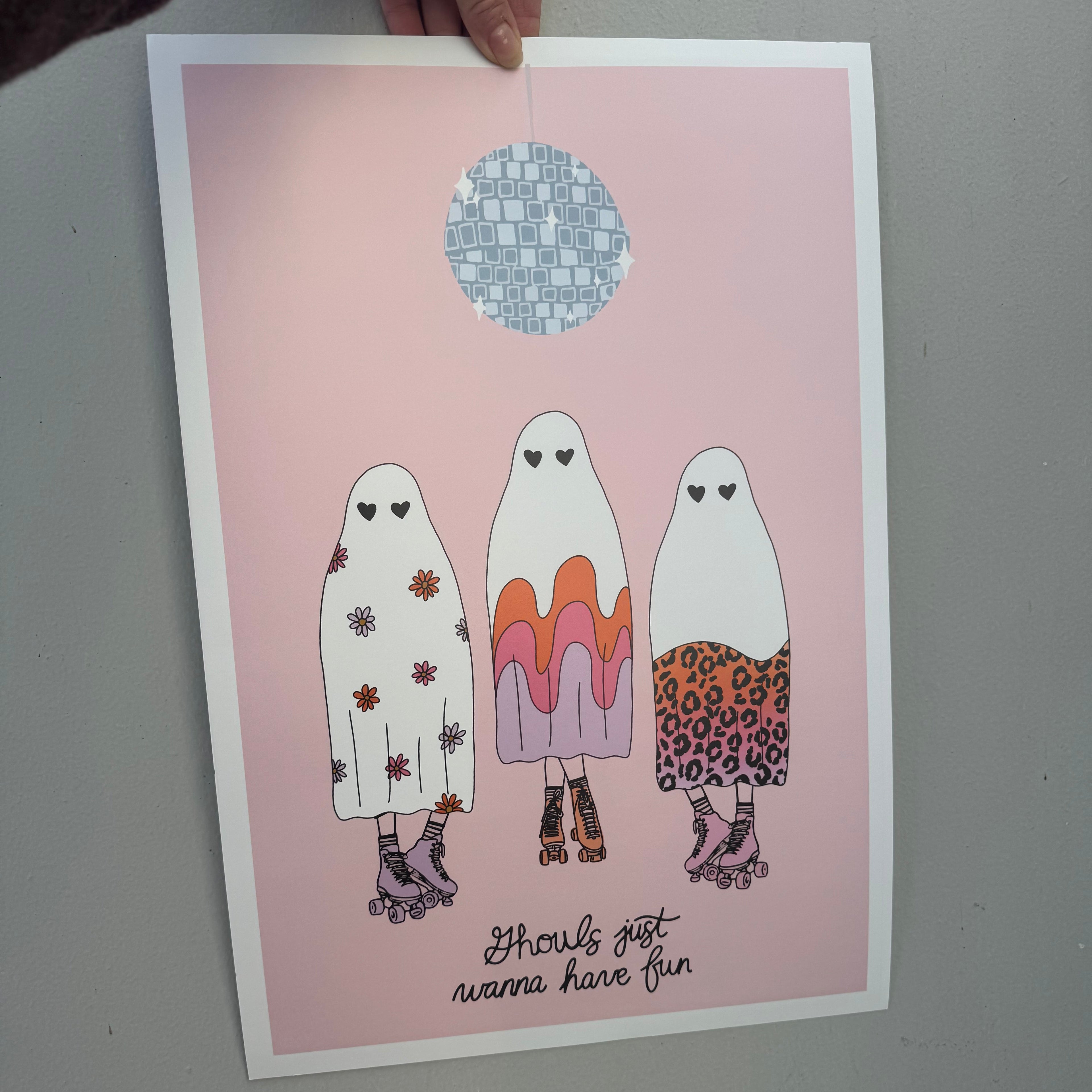 Illustrated paper dolls on a pink card with text, held by a hand.