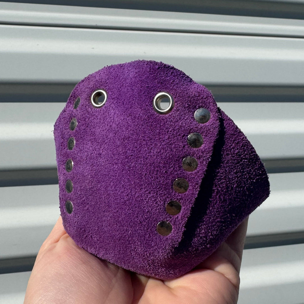 Hand holding a purple leather wallet against a metallic background