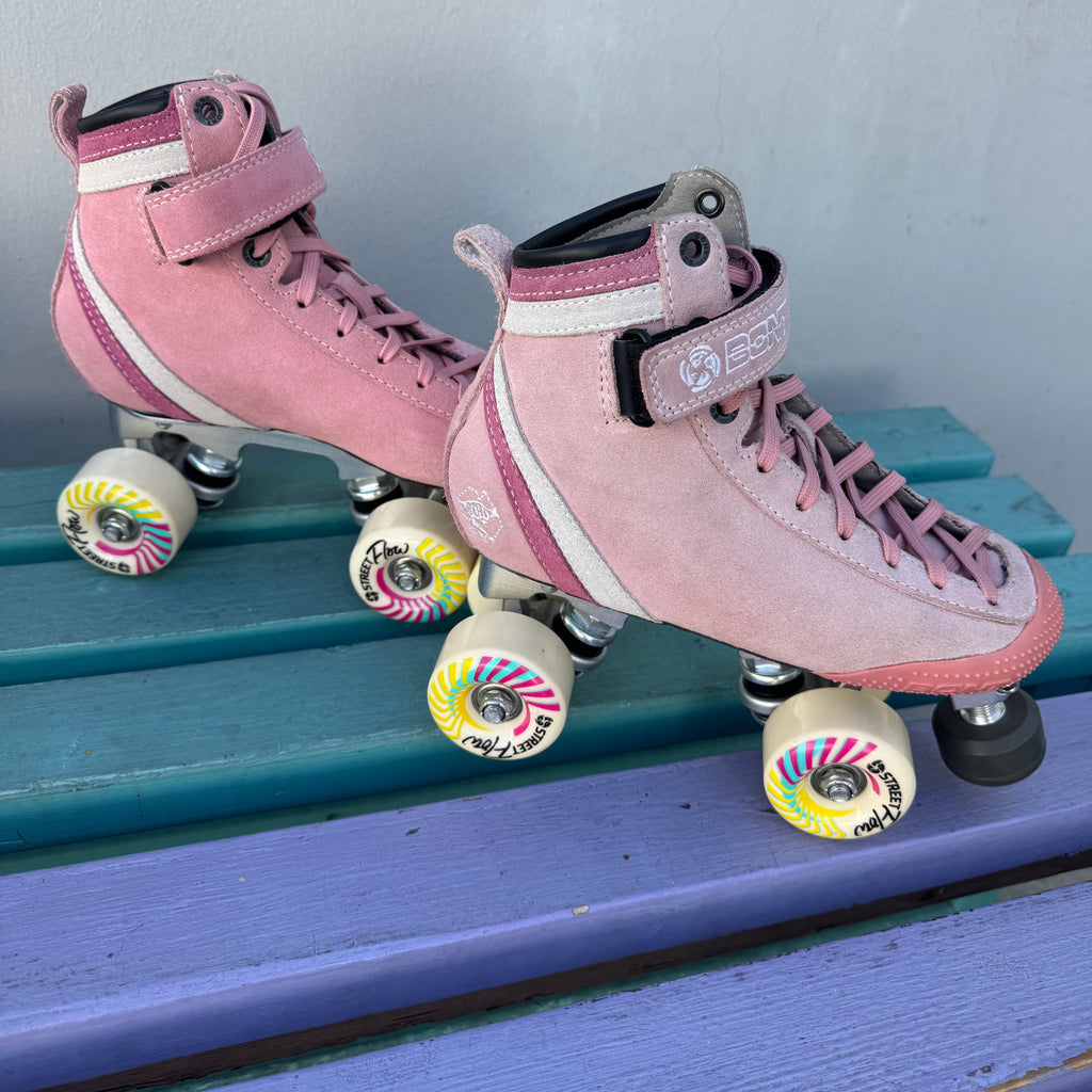 pink suede roller skates on purple bench